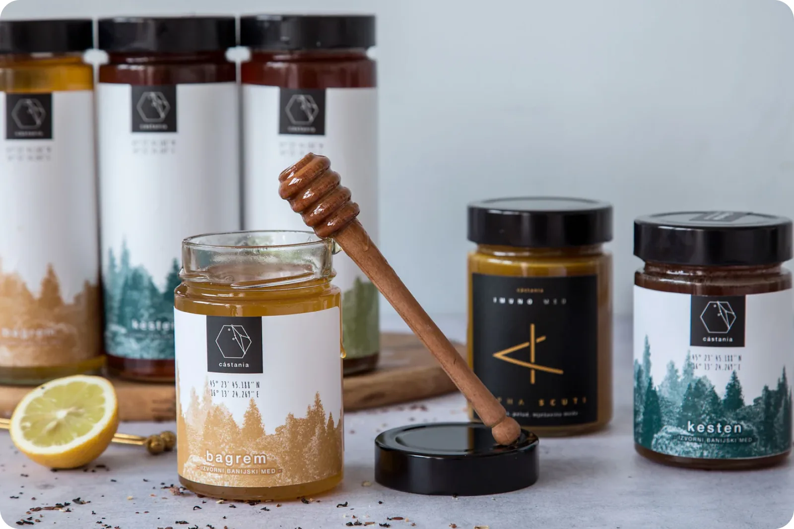 A group of Castania honey jars with a wooden dipper and a lemon.