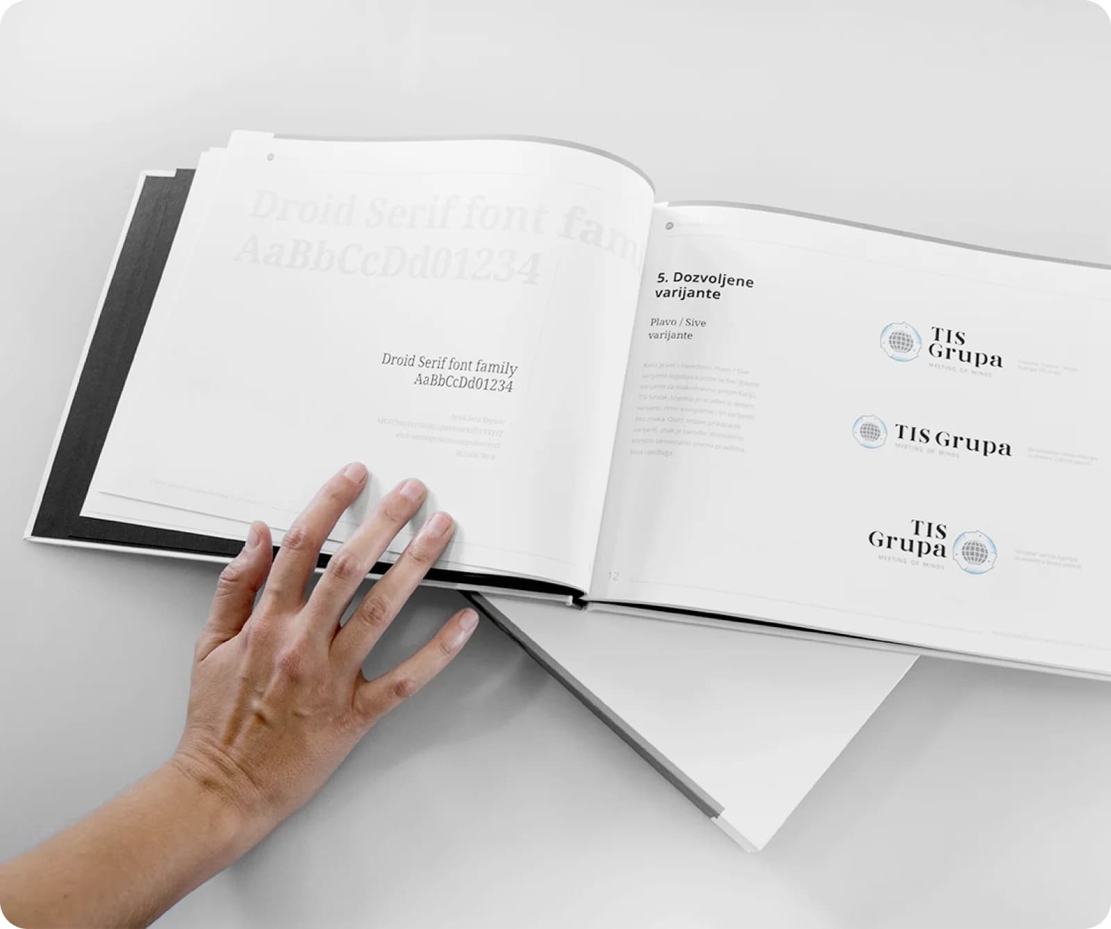 The TIS Grupa book of graphic standards, open to the permitted logo variants and the Droid Serif typeface.