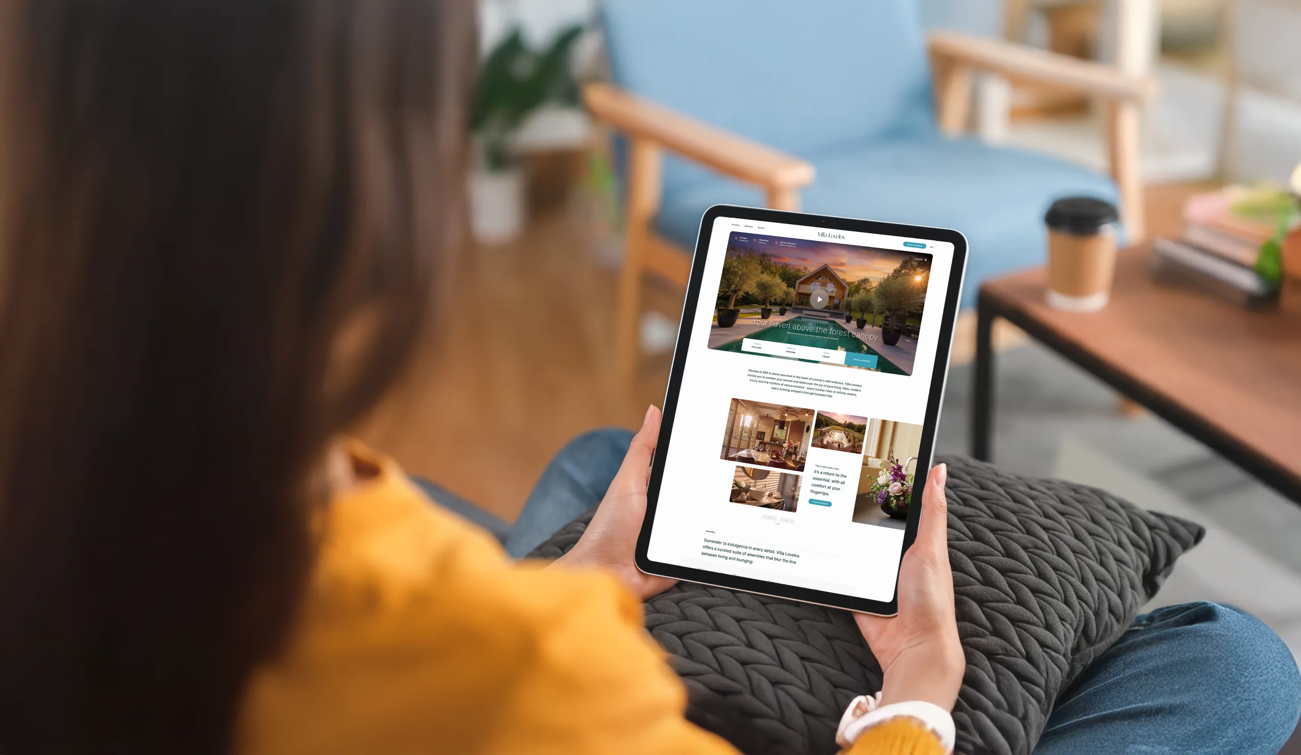 A woman on a sofa holding a tablet that displays the Vila Lovelos booking website.